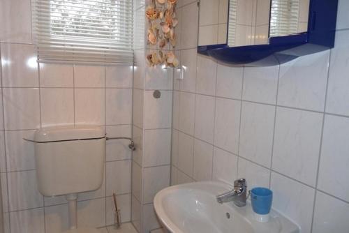 un bagno piastrellato bianco con servizi igienici e lavandino di Ferienhaus nahe Stechlinsee a Neuglobsow