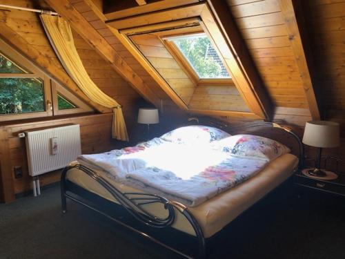 een slaapkamer met een bed op een zolder met 2 ramen bij Blockhaus am Waldrand in Brieselang