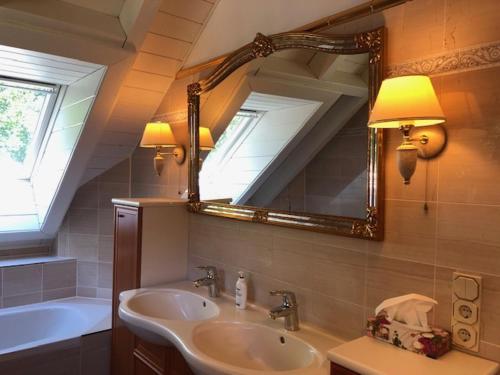 een badkamer met een wastafel, een spiegel en een bad bij Blockhaus am Waldrand in Brieselang