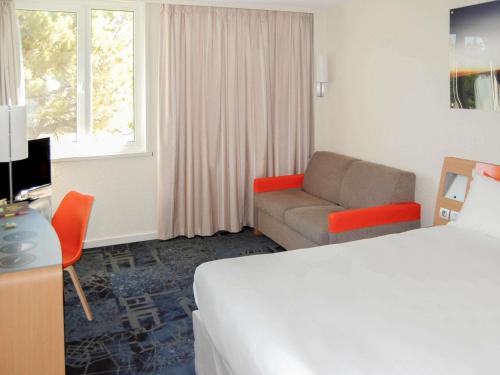 una habitación de hotel con una cama y un sofá en ibis Styles Marseille Aéroport, en Vitrolles