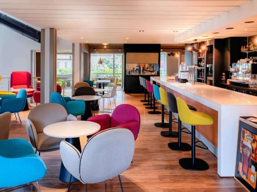 un bar con mesas y sillas coloridas en un restaurante en Novotel Metz Amnéville, en Maizières-lès-Metz