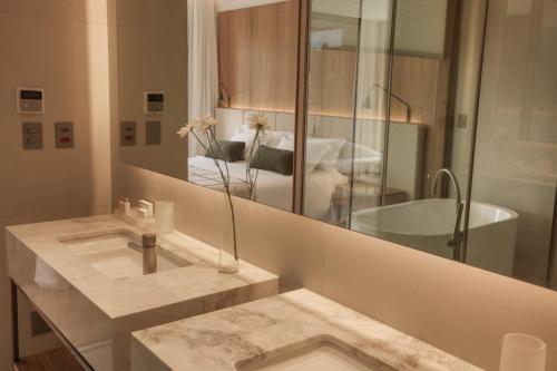 a bathroom with a sink and a mirror and a tub at Hotel Vila Inglesa in Campos do Jordão