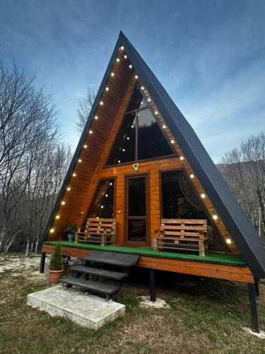 Una cabaña de madera con techo negro y luces. en Martvili canyon cottage Love nest, en Martvili