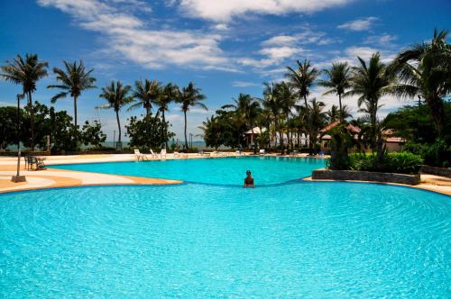 a person in a pool with palm trees in the background at Sunshine Beach Condotel in Na Jomtien