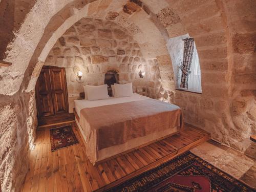 une chambre avec un lit dans une pièce en pierre dans l'établissement Hanzade Cappadocia, à Gorëme