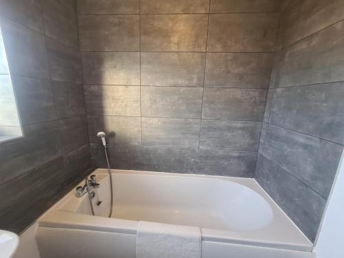 a white bath tub in a bathroom with gray tiles at Stylish 3 bed close to Nissan in Sunderland