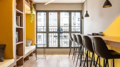 a kitchen with a bar with chairs and a window at Studio Metrô Tucuruvi in São Paulo