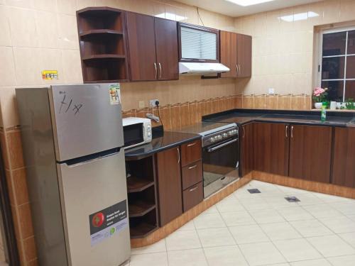 a kitchen with a stainless steel refrigerator and wooden cabinets at Gorgeous Villa Rooms opposite to Mirdif City Center in Dubai