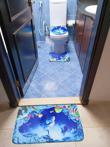 a bathroom with a toilet with a fish themed floor mat at Gorgeous Villa Rooms opposite to Mirdif City Center in Dubai