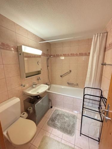 a bathroom with a tub and a sink and a toilet at BergSee Apartament Laax in Laax