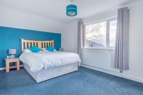 a blue bedroom with a bed and a window at Groeslon Uchaf in Caernarfon