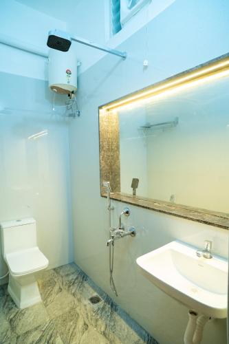 a bathroom with a sink and a toilet and a mirror at Le Predhu Villa in Pondicherry