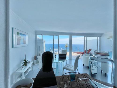 een woonkamer met een tafel en stoelen en de oceaan bij Exclusive Ocean Views in Los Realejos