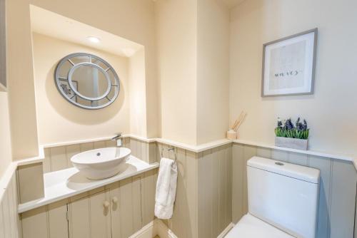 a bathroom with a sink and a toilet and a mirror at 4 Bed in Instow oc-clevv in Instow