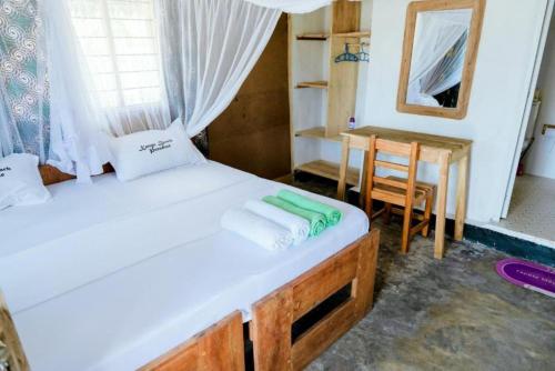 ein Schlafzimmer mit einem Bett, einem Tisch und einem Spiegel in der Unterkunft Quiet beachfront hideaway - Mafia Island - 2355 in Bweni