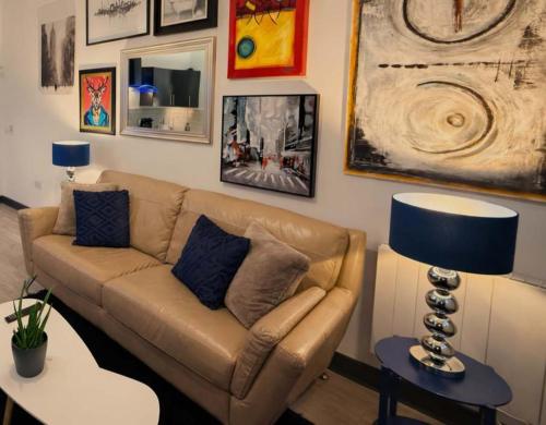 un soggiorno con divano e immagini appese al muro di The Plaza, King 1 Bedroom Suite by The Hive WA1 a Warrington
