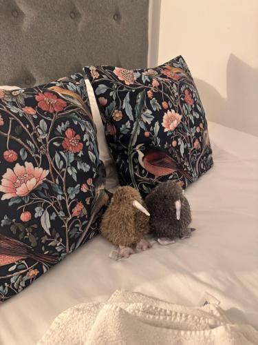 ノリッジにあるChloes Retreatの枕の横のベッドに座っている2匹のぬいぐるみ