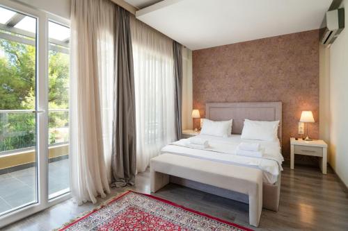 een slaapkamer met een bed en een groot raam bij Spa Villa Sunny in Hanioti