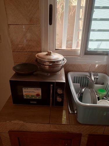een magnetron met een pan erop naast een gootsteen bij Studio meublé prestige in Niamey
