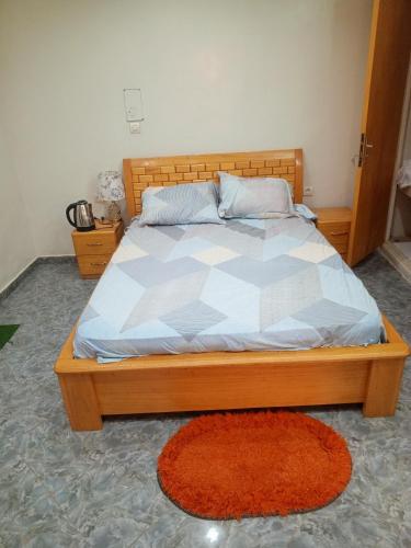 een bed met een houten frame en een rood tapijt bij Studio meublé prestige in Niamey