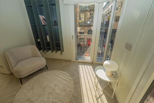 een woonkamer met een stoel, een tafel en ramen bij Dune Luxury Residence in Turijn