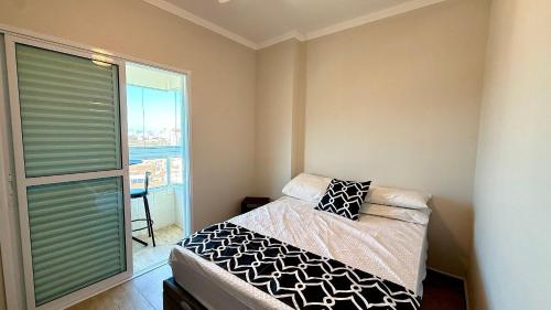 een slaapkamer met een bed en een groot raam bij Condomínio Edifício Viena in Vila Balneária