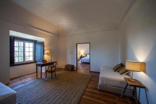 een slaapkamer met een bed, een tafel en een spiegel bij Palácio Ficalho in Bicas