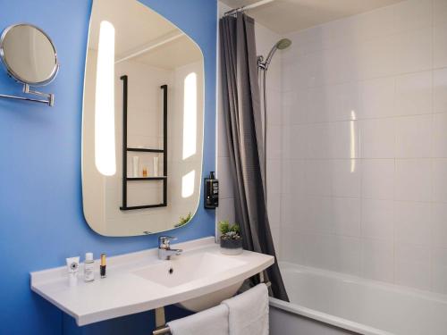 a bathroom with a sink and a mirror and a tub at ibis Saint-Nazaire - Trignac in Trignac