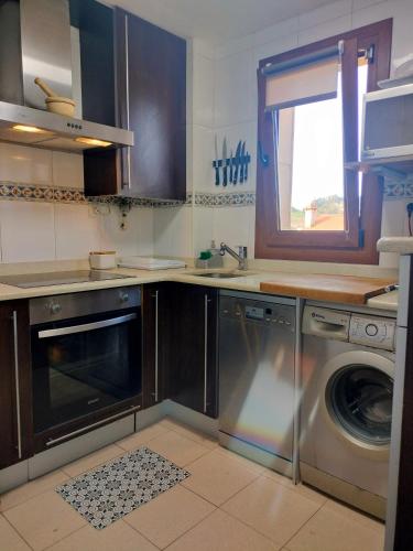 a kitchen with a sink and a washing machine at La Casuca del Pas - dúplex con terrazas y vistas in Puente Arce