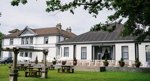 a white building with picnic tables in front of it at Manor Park Country House in Swansea