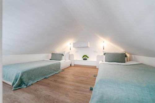 twee bedden in een kamer met witte muren en houten vloeren bij Yucca Park duplex in Adeje