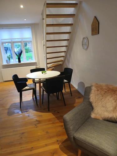 a living room with a table and chairs and a staircase at Lejlighed ved stranden og centrum in Fredericia