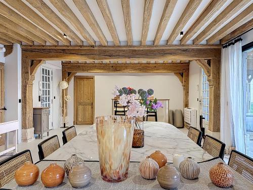 una sala da pranzo con tavolo e vasi sopra di Villa Elysia YourHostHelper a Touques