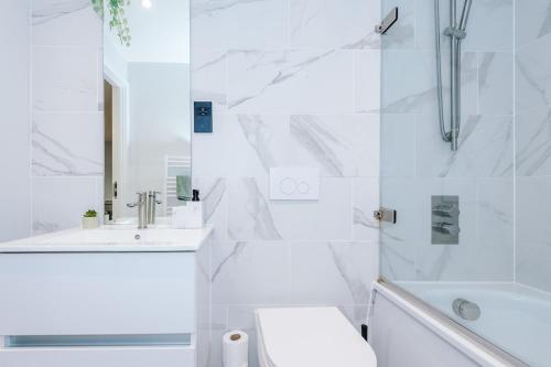 a white bathroom with a tub and a toilet and a sink at Birmingham City centre, Pool table, Spacious in Birmingham