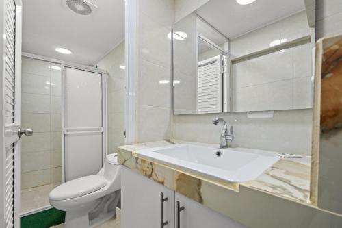 a bathroom with a sink and a toilet and a mirror at Casa Hotel Ecosuite in Cali