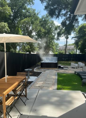 a patio with a table and an umbrella and a grill at Hot Tub Pool Table Fire Pit 5min to Uptown in Charlotte
