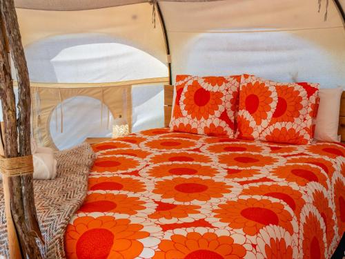 El RosarioLa Colmena Glamping Zangano的床上铺着橙白相间的羽绒被，还有枕头。