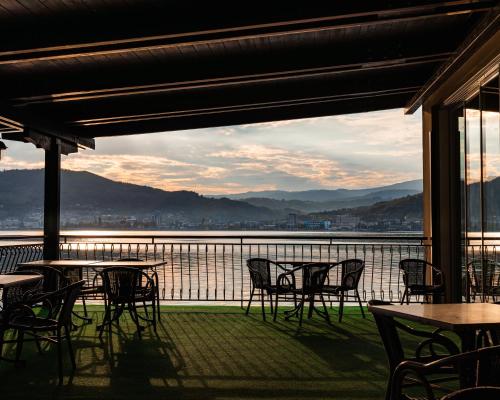 Un patio con mesas y sillas y vista al agua. en Pensiunea Taka, en Orşova