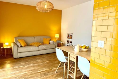 ein Wohnzimmer mit Sofa und Tisch in der Unterkunft Le Petit Jaune - Studio - Terrasse & Plage Pointe Rouge in Marseille