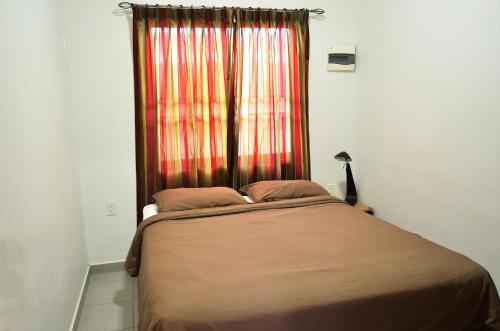 a bed in a room with a window with a curtain at Rachel's Apartments in Paramaribo