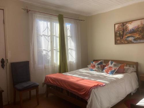 ein Schlafzimmer mit einem Bett, einem Fenster und einem Stuhl in der Unterkunft Habitaciones en Casa de la Playa! in Quintero