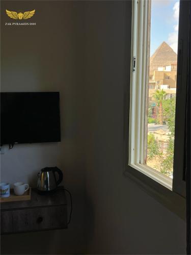 a room with a window and a tv and a table at Zak Pyramids Inn in Cairo