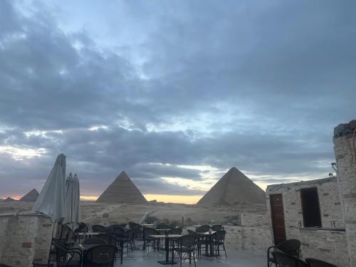 een uitzicht op de piramides vanaf een patio met tafels en stoelen bij Middle East pyramids veiw &spa in Caïro