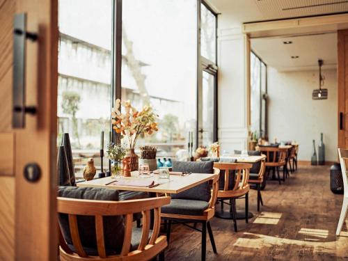 ein Restaurant mit Tischen, Stühlen und Fenstern in der Unterkunft Hotel Mondial am Dom Cologne MGallery in Köln