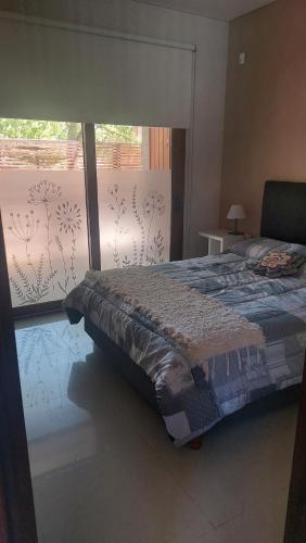 a bedroom with a bed and a large window at dpto SanLuis in Valeria del Mar