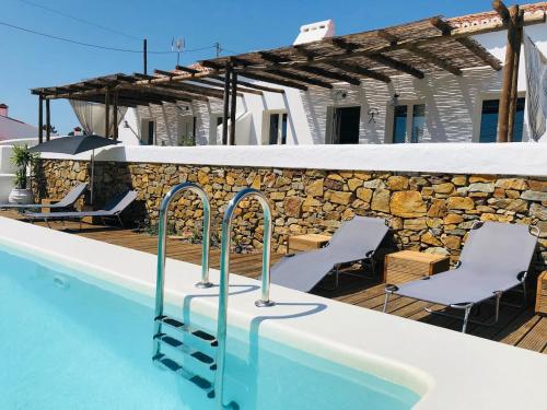una piscina con sedie e un muro in pietra di Casa Poente - Casas de Seixe a São Teotónio
