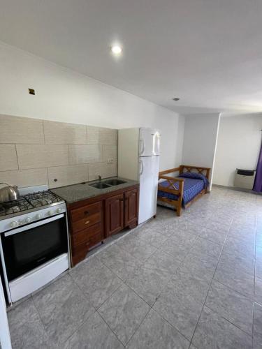 a kitchen with a stove and refrigerator and a bed at Departamentos Los Manantiales in Villa Gesell