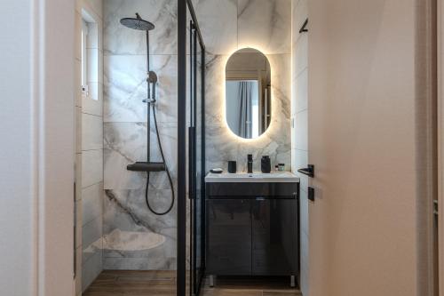 托隆Noma Suites Tolo的带淋浴和盥洗盆及镜子的浴室