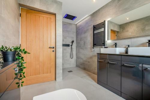 een badkamer met een wastafel en een houten deur bij 12 Bed in Pancrasweek oc-lvbb24 in Pancrasweek