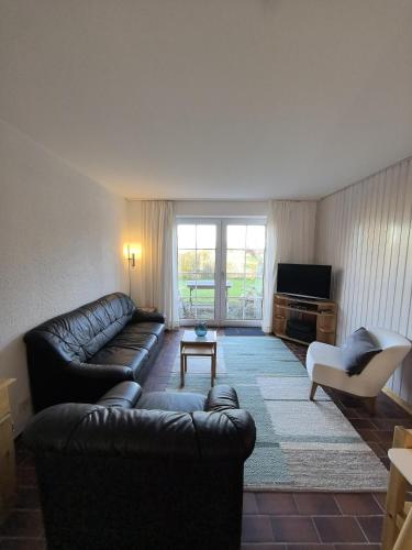 a living room with a leather couch and a tv at Auszeit am Feldrand in Lensahn